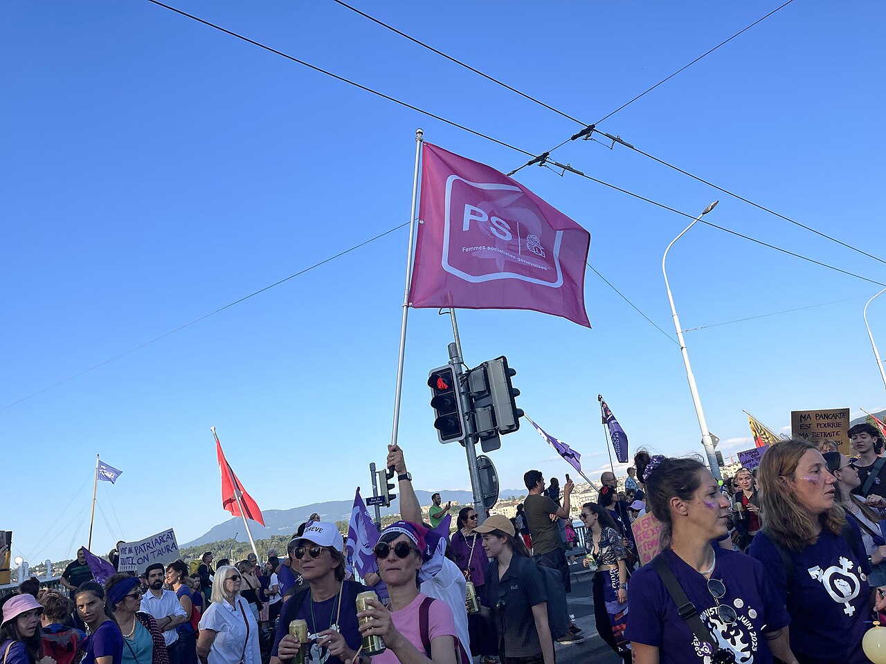 Menschen beim feministischen Streik in Genf 2023 mit einer Fahne der sozialistischen Frauen.